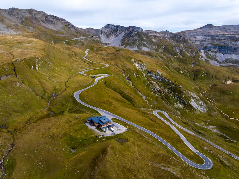 Drohnenaufnahme einer serpentinenreichen Bergstraße durch alpines Hochgebirgsgelände