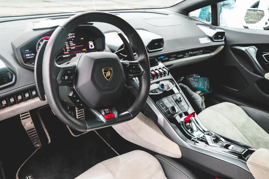 Lenkrad und Armaturenbrett eines schwarzen Lamborghini – Detail-Aufnahme des Sportwagen-Interieurs