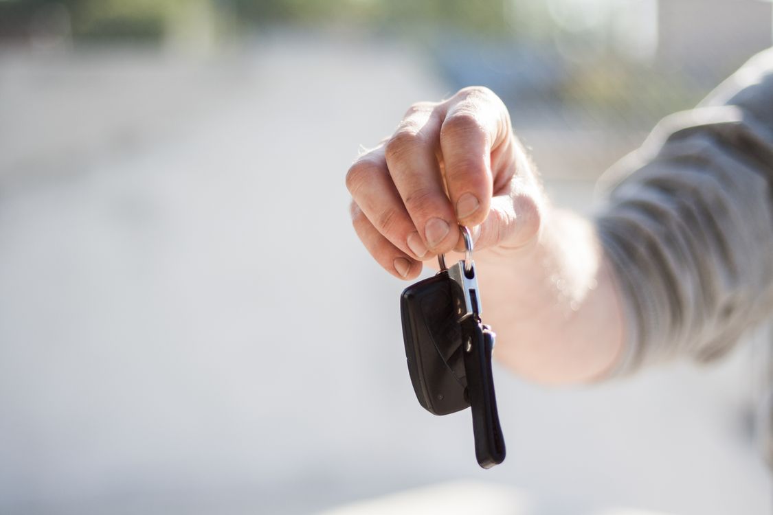 Person übergibt Autoschlüssel – Symbol für die Fahrzeugmiete über Drivable