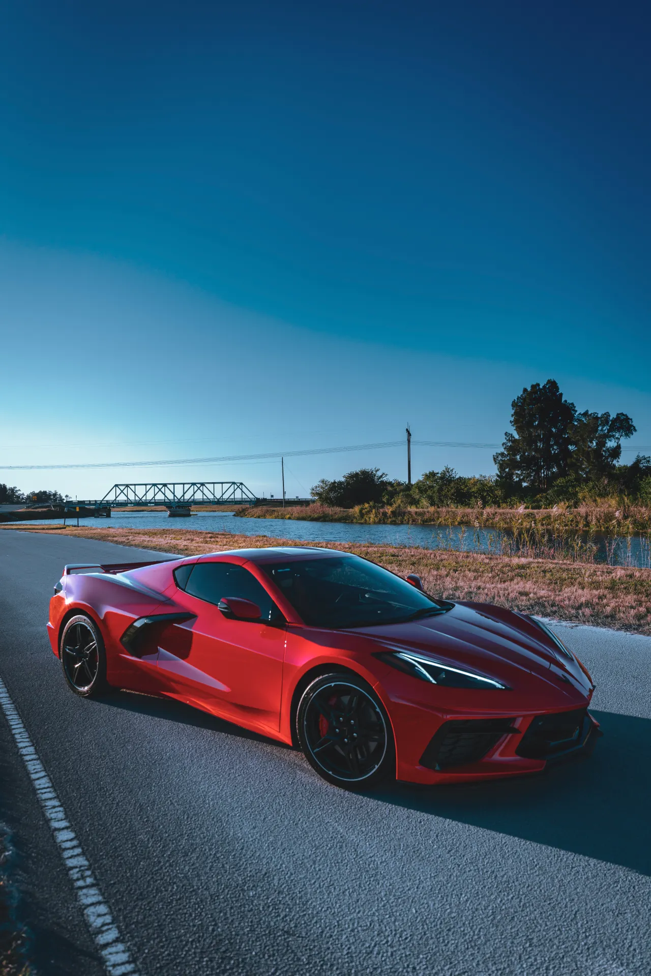 Rote Chevrolet Corvette auf einer sonnigen Landstraße – Sportwagen mieten leicht gemacht
