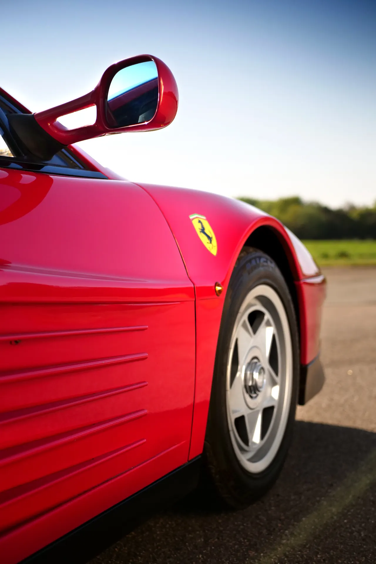 Roter Ferrari-Sportwagen in dynamischer Seitenansicht auf sonnenbeschienener Strasse