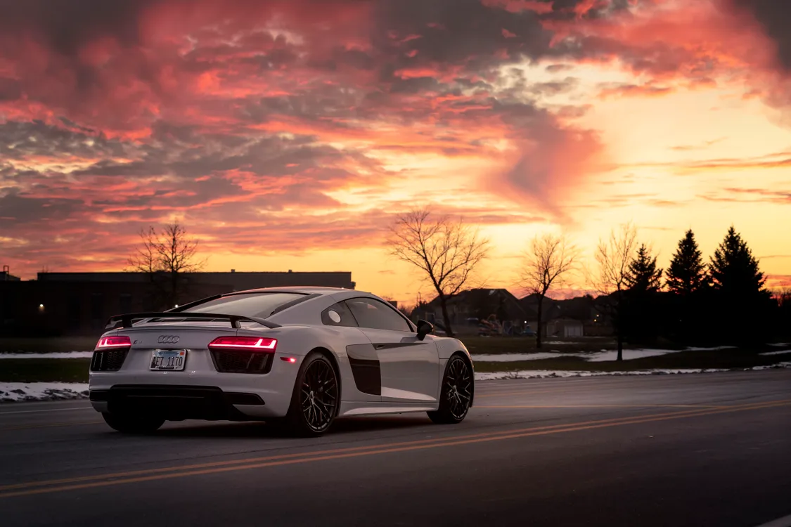 Weißer Sportwagen bei Sonnenuntergang — Golden-Hour-Licht betont Lackierung und Karosserielinien optimal