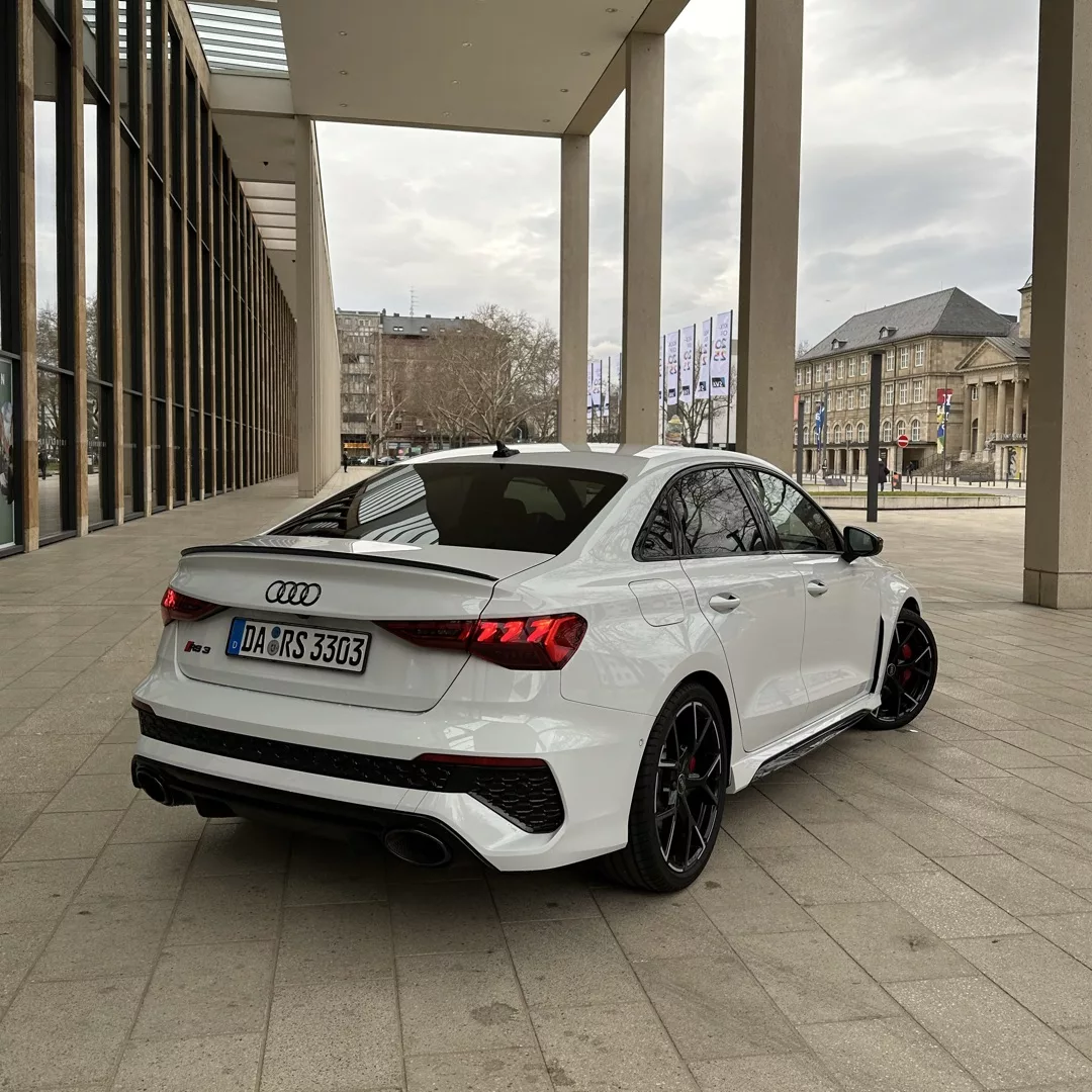 Audi RS3 Limousine in Weiß, Rückansicht, urbanes Setting mieten.
