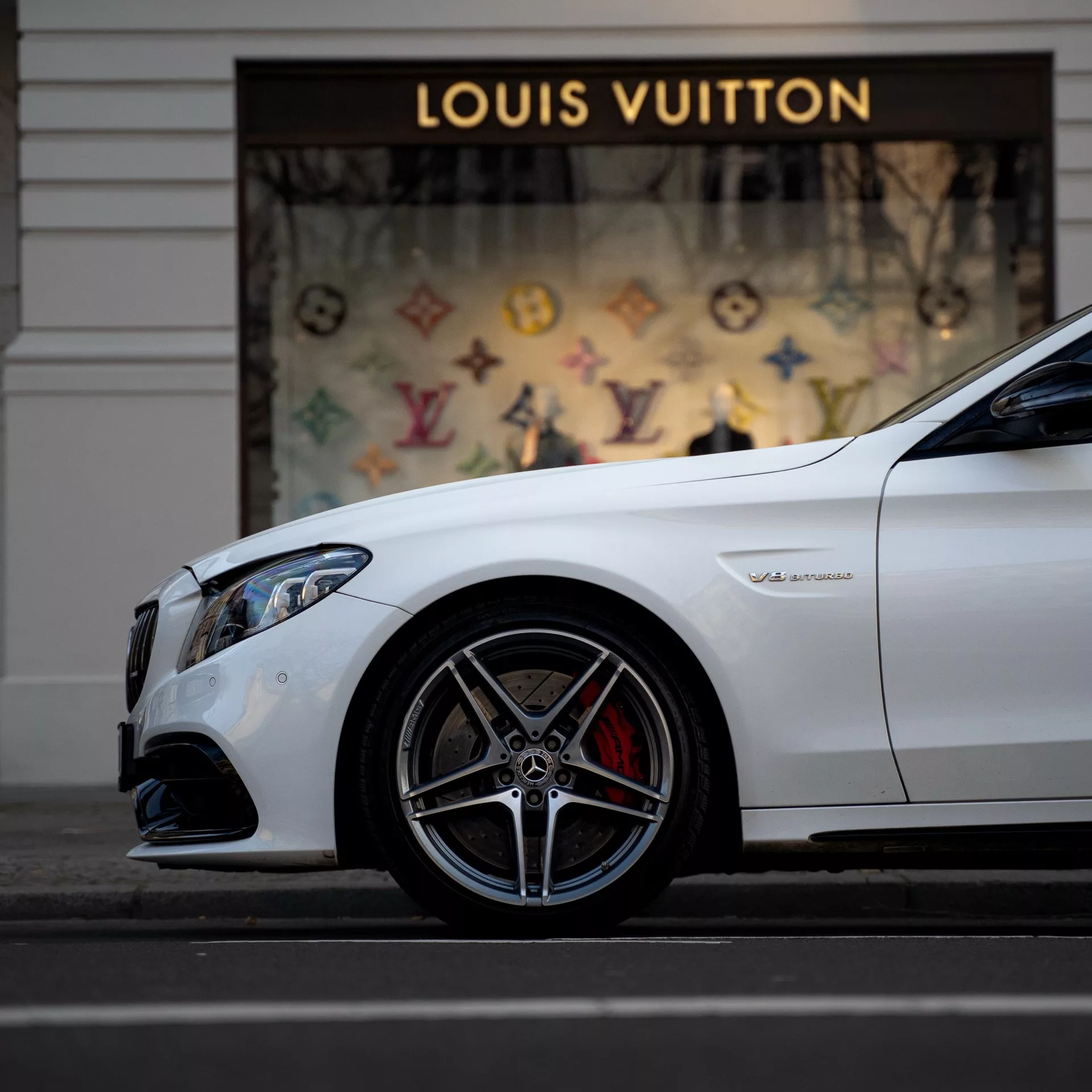 Mercedes C63s V8 BiTurbo in Weiß, Seitenansicht vor Geschäft mieten.