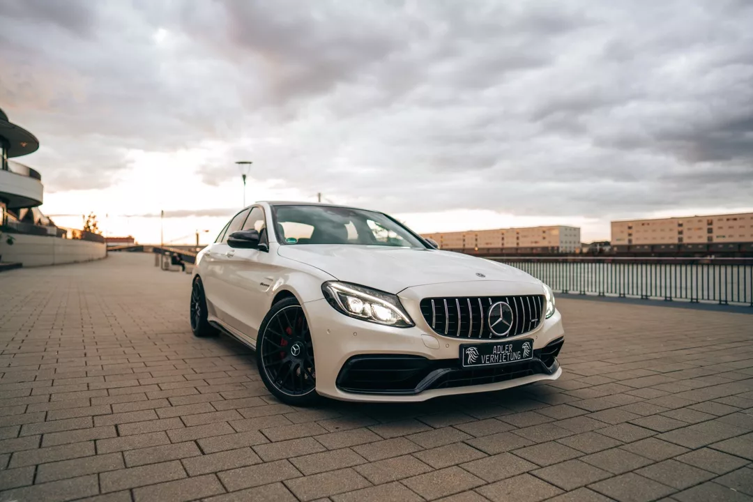 Mercedes C63 AMG in Weiß mieten - Frontansicht auf Straße.