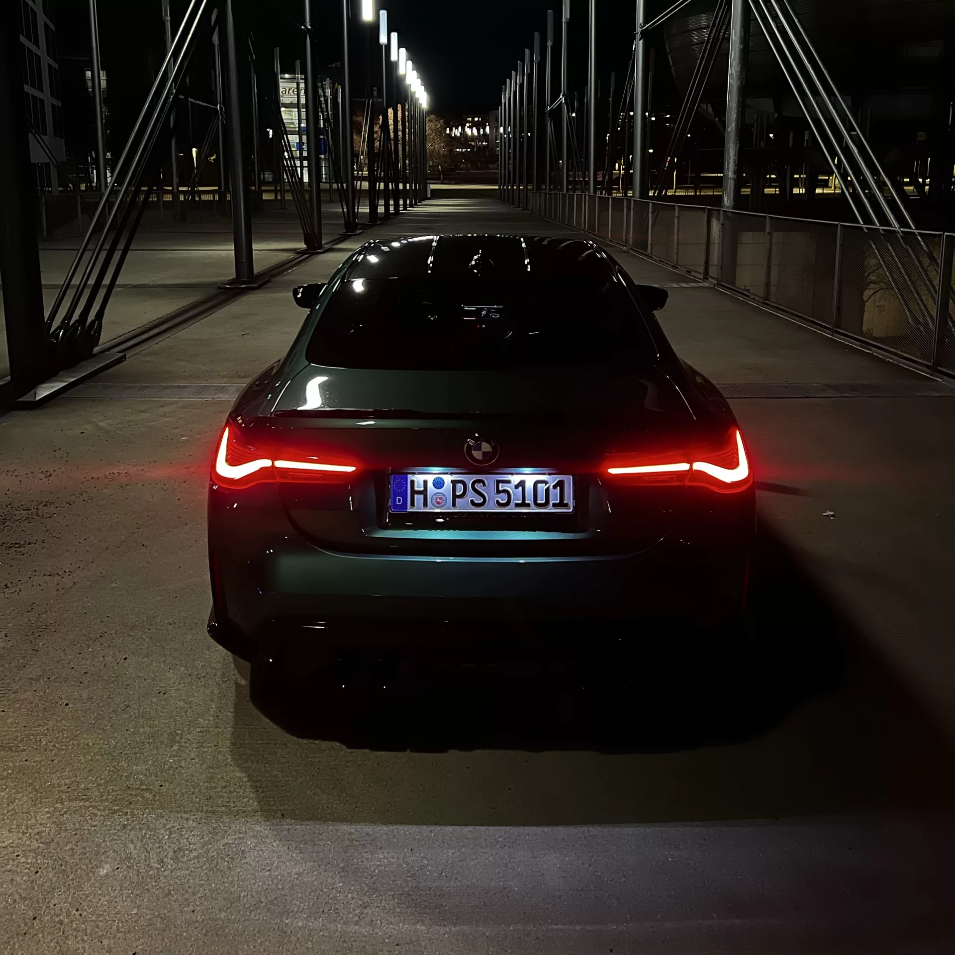 BMW M4 Competition in Dunkelgrün von hinten bei Nacht mieten.