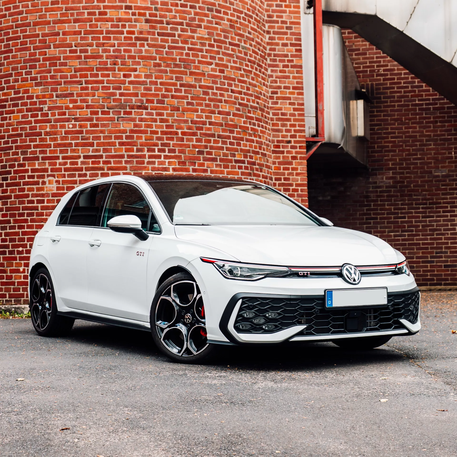 Golf 8 GTI Facelift in Weiß vor Ziegelwand mieten