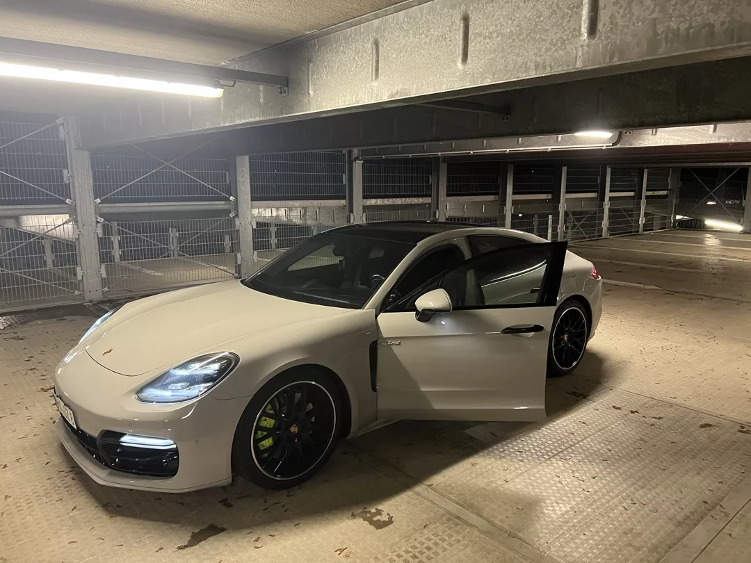 Porsche Panamera in Weiß mit geöffneter Tür im Parkhaus mieten.
