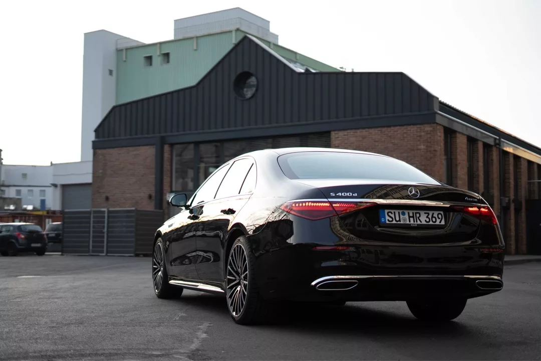 Mercedes Benz S-Klasse in Schwarz, Heckansicht, vor Gebäude mieten.