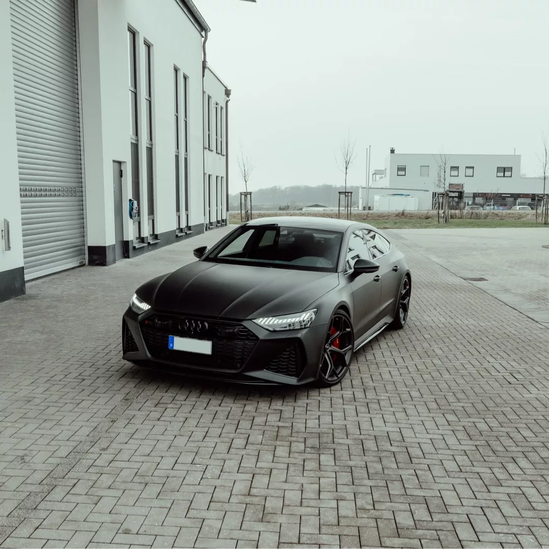 Audi RS7 Performance in Mattgrau mieten - Vorderansicht auf Pflasterstein.
