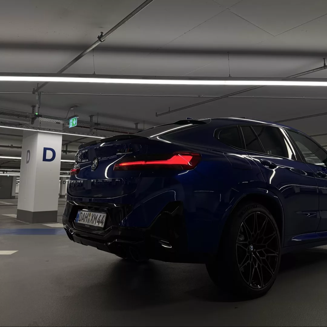 BMW X4 M Competition in Blau, Heckansicht im Parkhaus mieten.