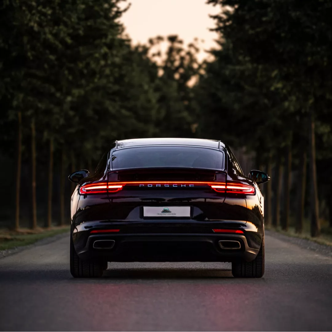 Porsche Panamera 4 in Schwarz von hinten bei Sonnenuntergang mieten.
