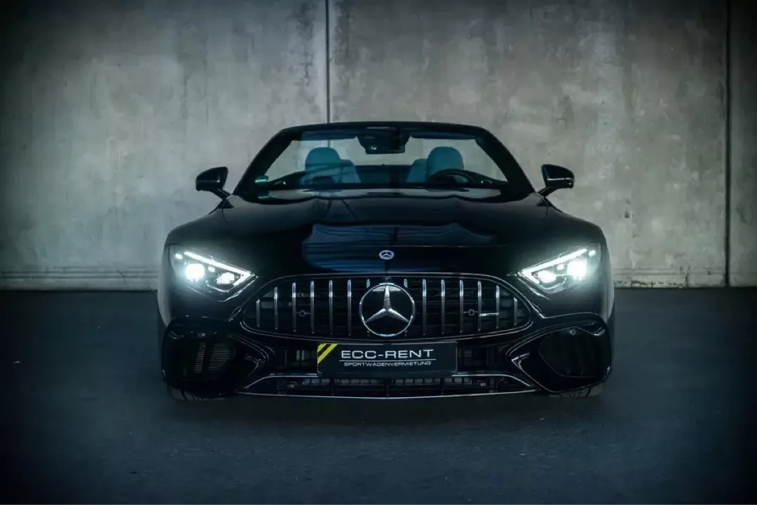Frontansicht eines schwarzen Mercedes-Benz SL63 AMG Roadsters mit eingeschalteten Scheinwerfern.