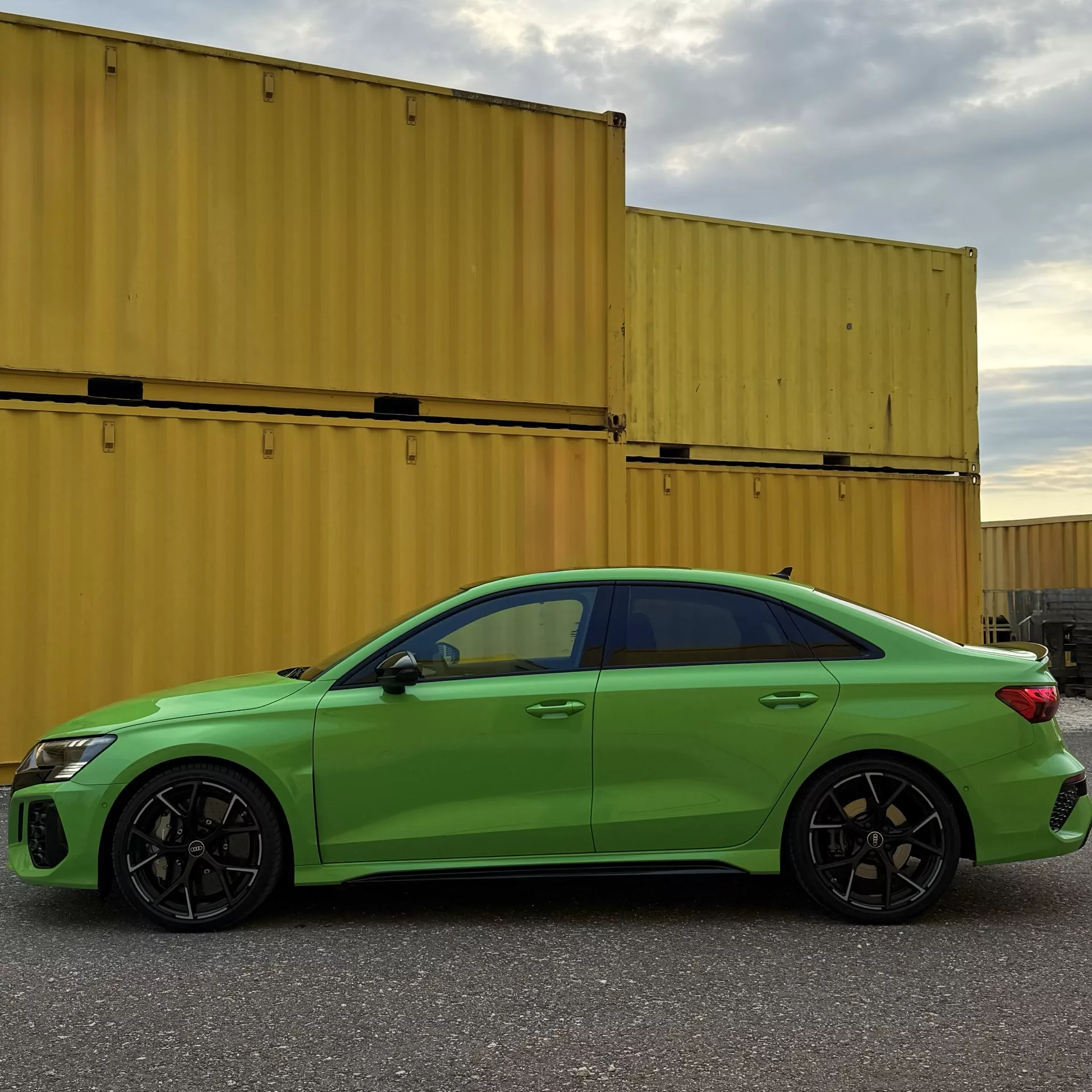 Audi RS3 in Grün von der Seite vor Containern mieten