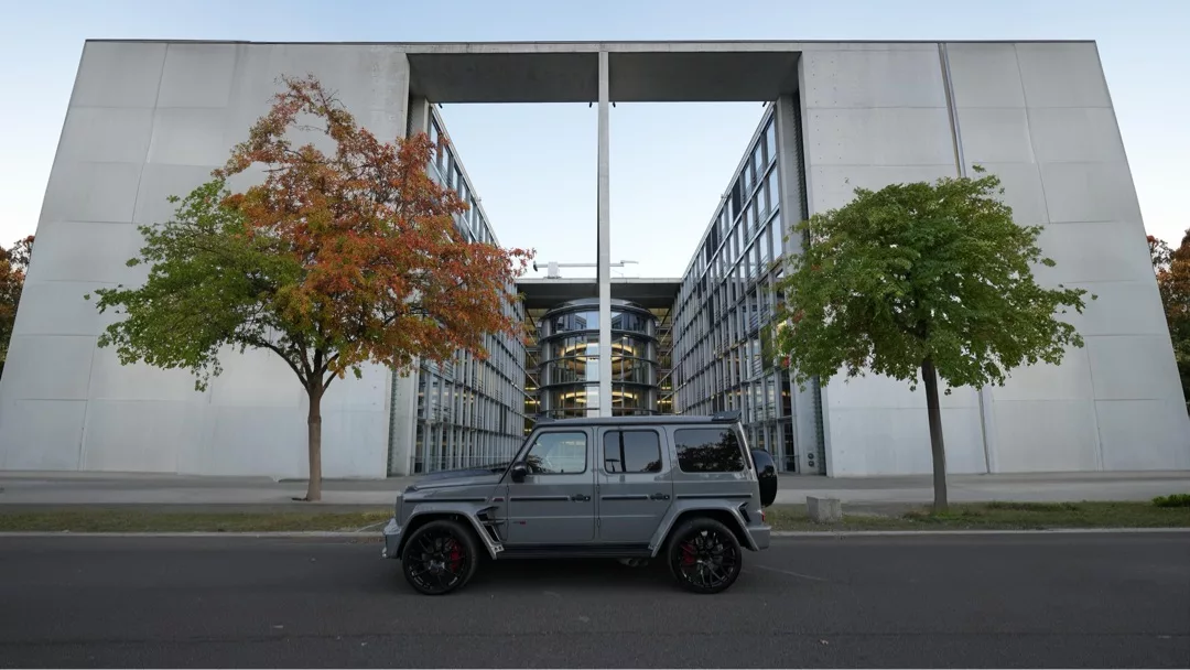 Brabus G700 in Grau von der Seite vor moderner Architektur mieten.