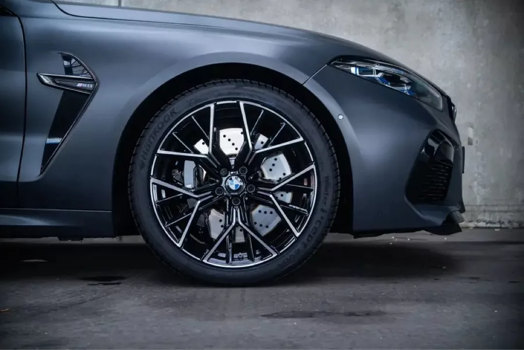 Nahaufnahme eines BMW M8 Gran Coupé-Rads vor einer Betonwand.