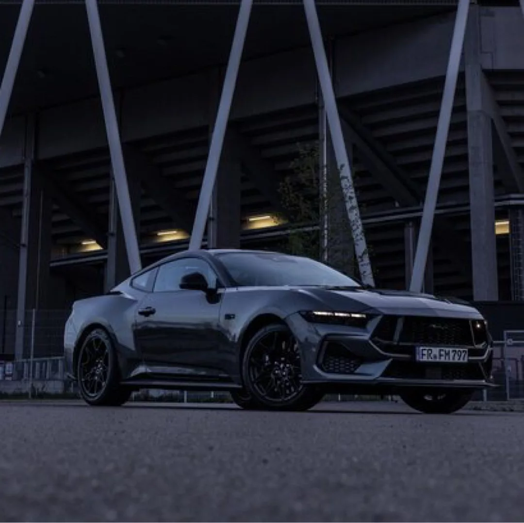 Ford Mustang GT (2024) in Dunkelgrau mieten - Seitenansicht bei Nacht.