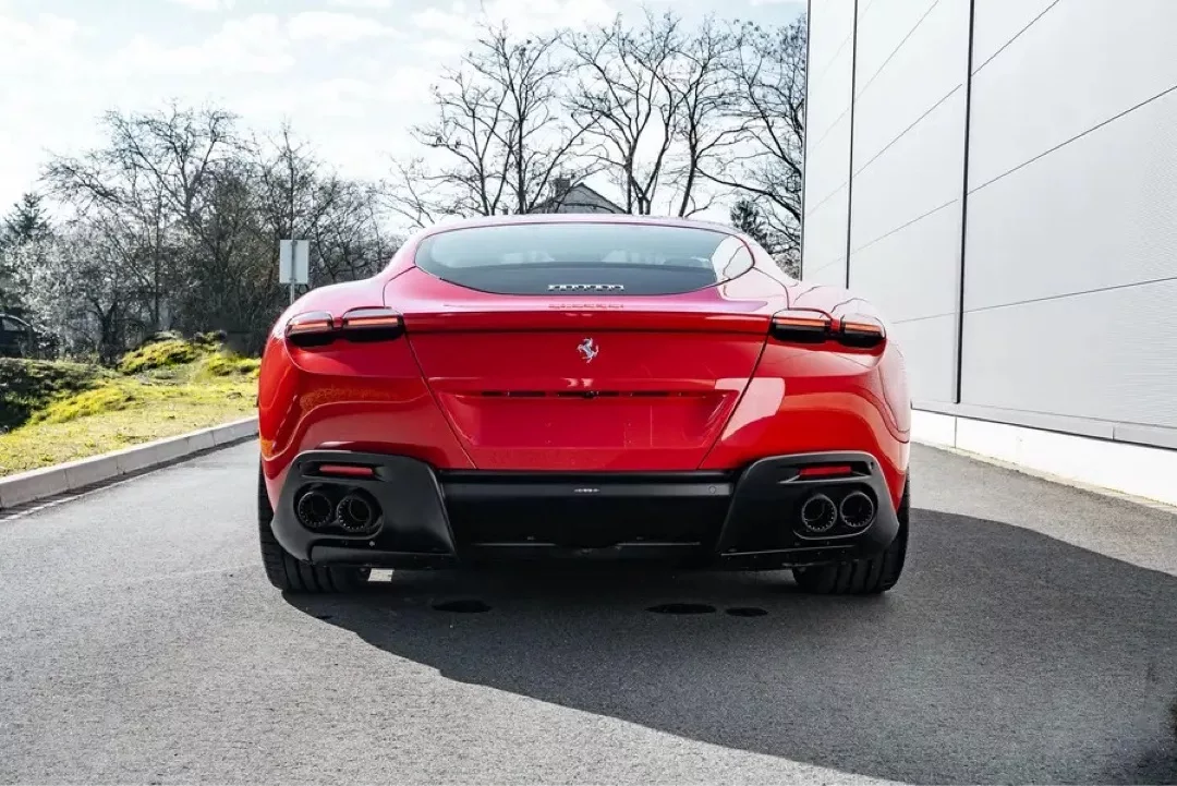 Roter Ferrari Roma von hinten auf einem Parkplatz bei Tag.