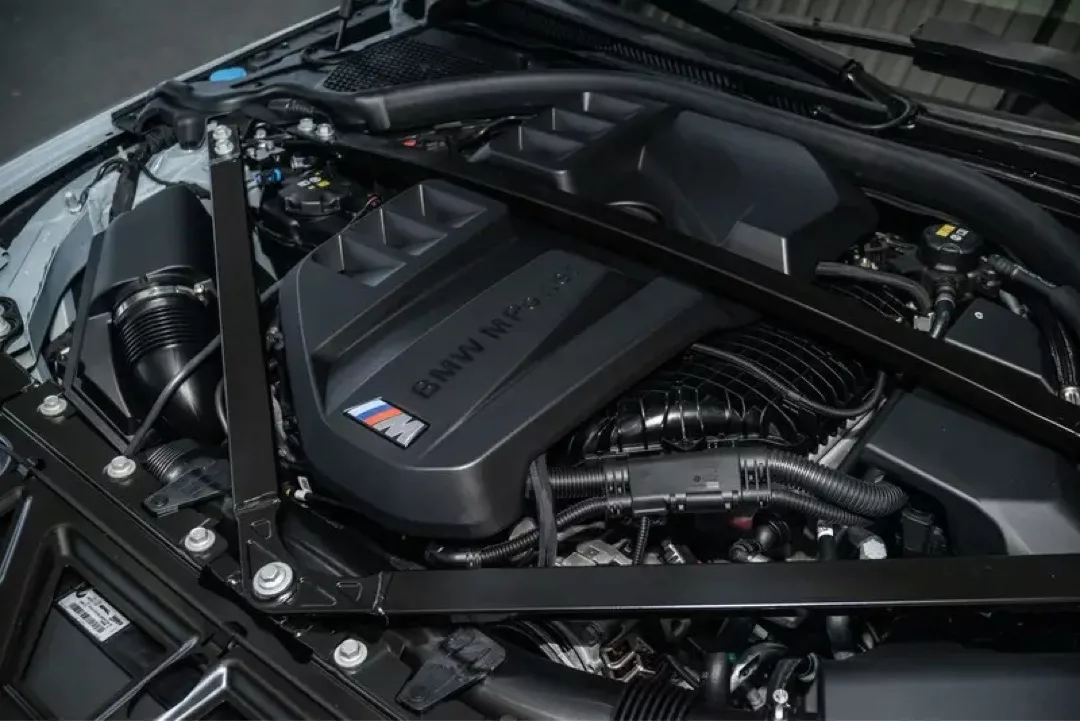 Motorraum eines BMW M3 Competition mit sichtbarem Motorabdeckung.