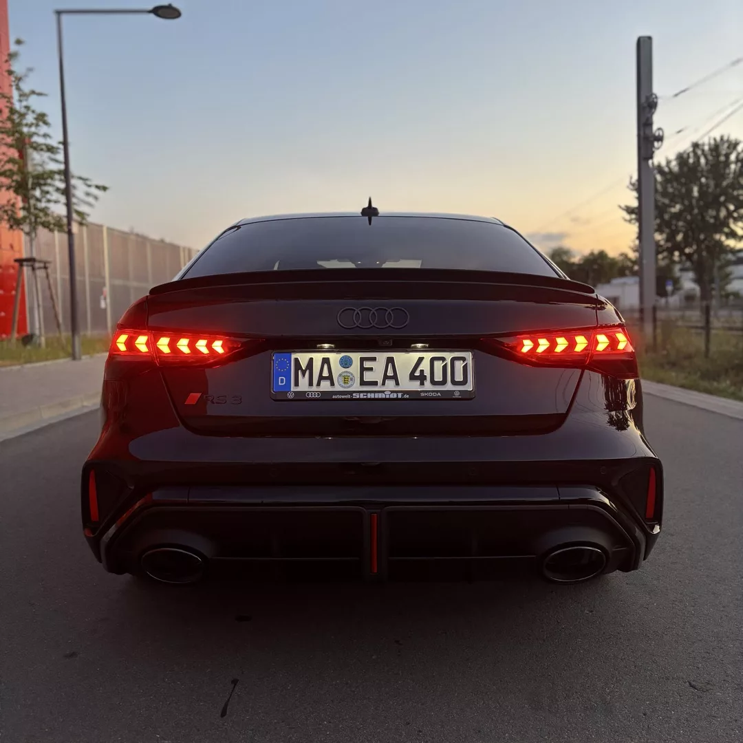 Audi RS3 von hinten bei Dämmerung, Bremslichter leuchten.