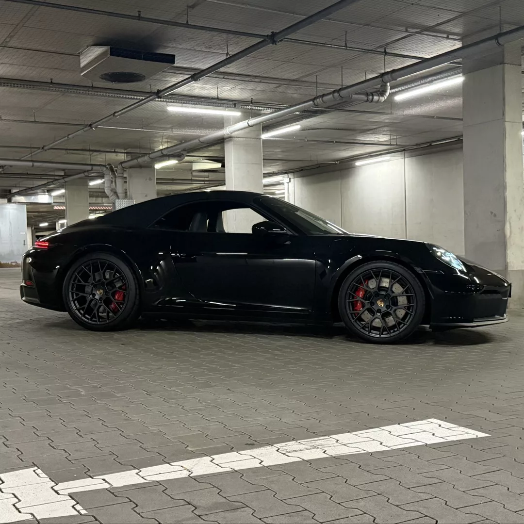 Porsche 911 Carrera GTS Cabrio in Schwarz, Seitenansicht im Parkhaus, mieten.