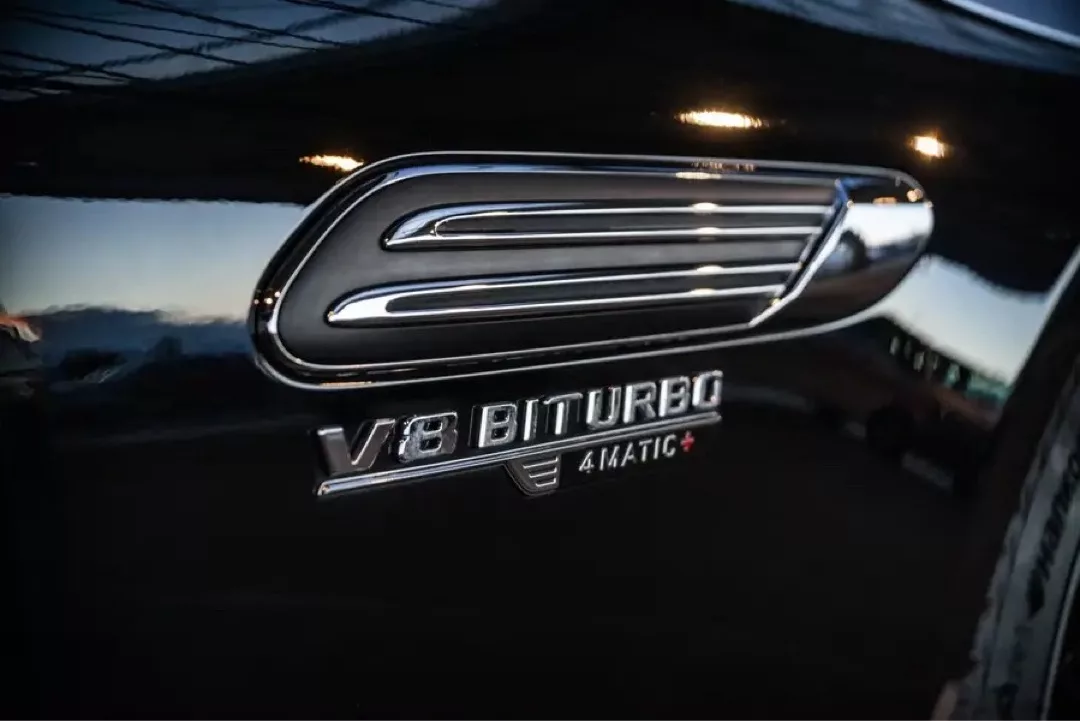 Nahaufnahme des V8 Biturbo 4MATIC+ Emblems an einem schwarzen Mercedes-Benz SL63 AMG Roadster.