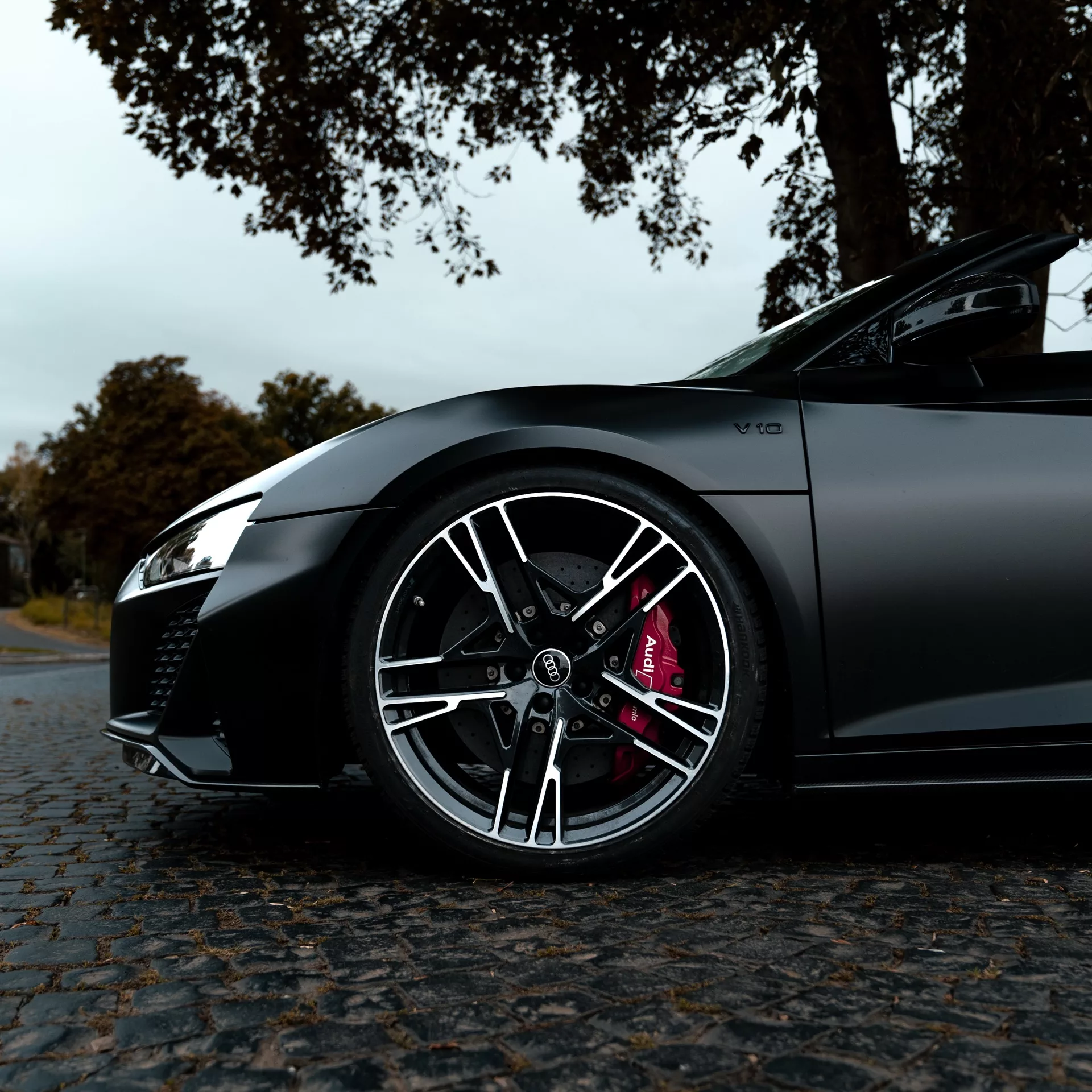 Audi R8 Spyder in Schwarz mieten - Nahaufnahme der Felgen und Karosserie.