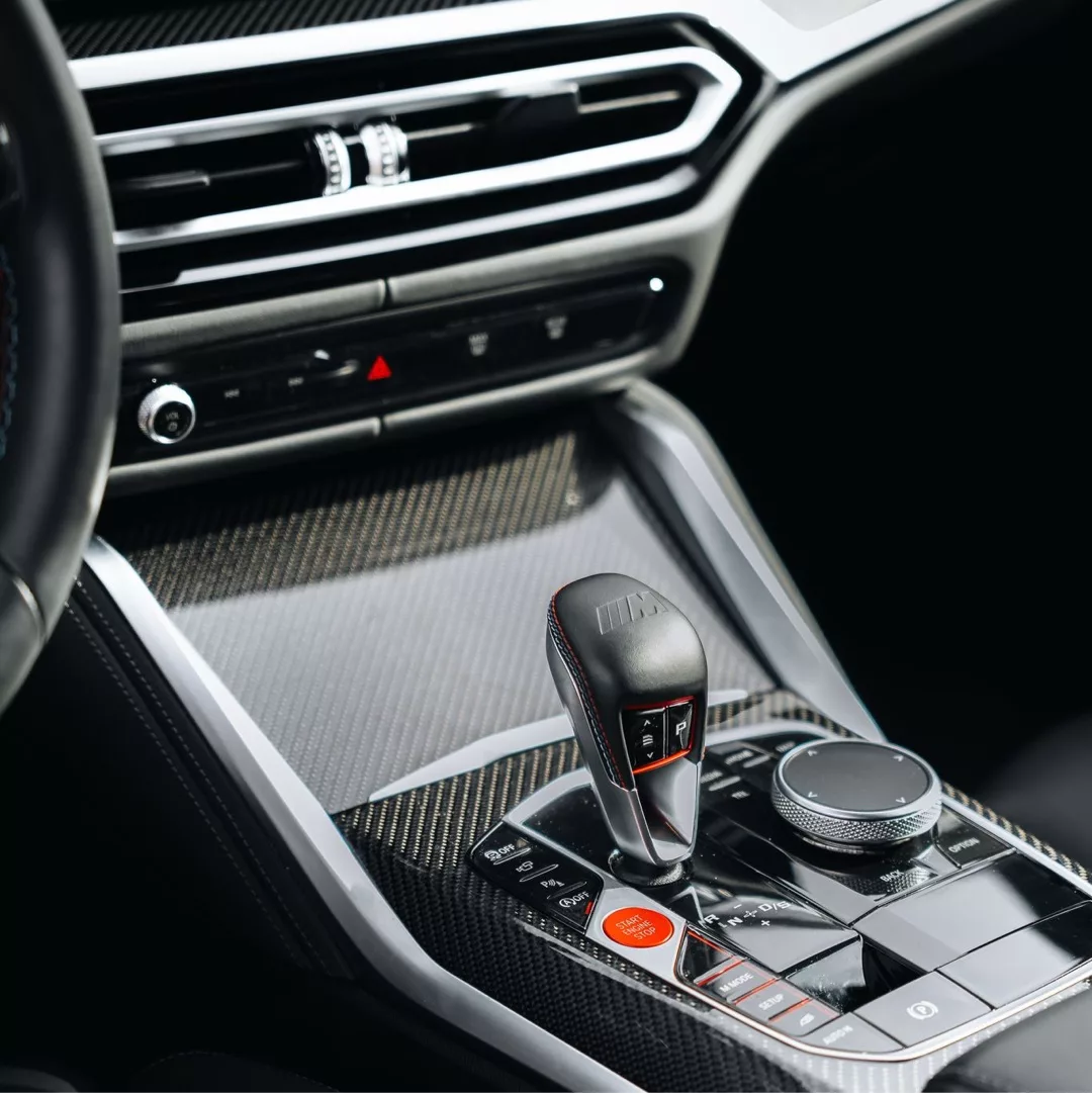 Mittelkonsole eines BMW M4 Competition xDrive mit carbonfaserverkleideter Schalthebelkonsole.