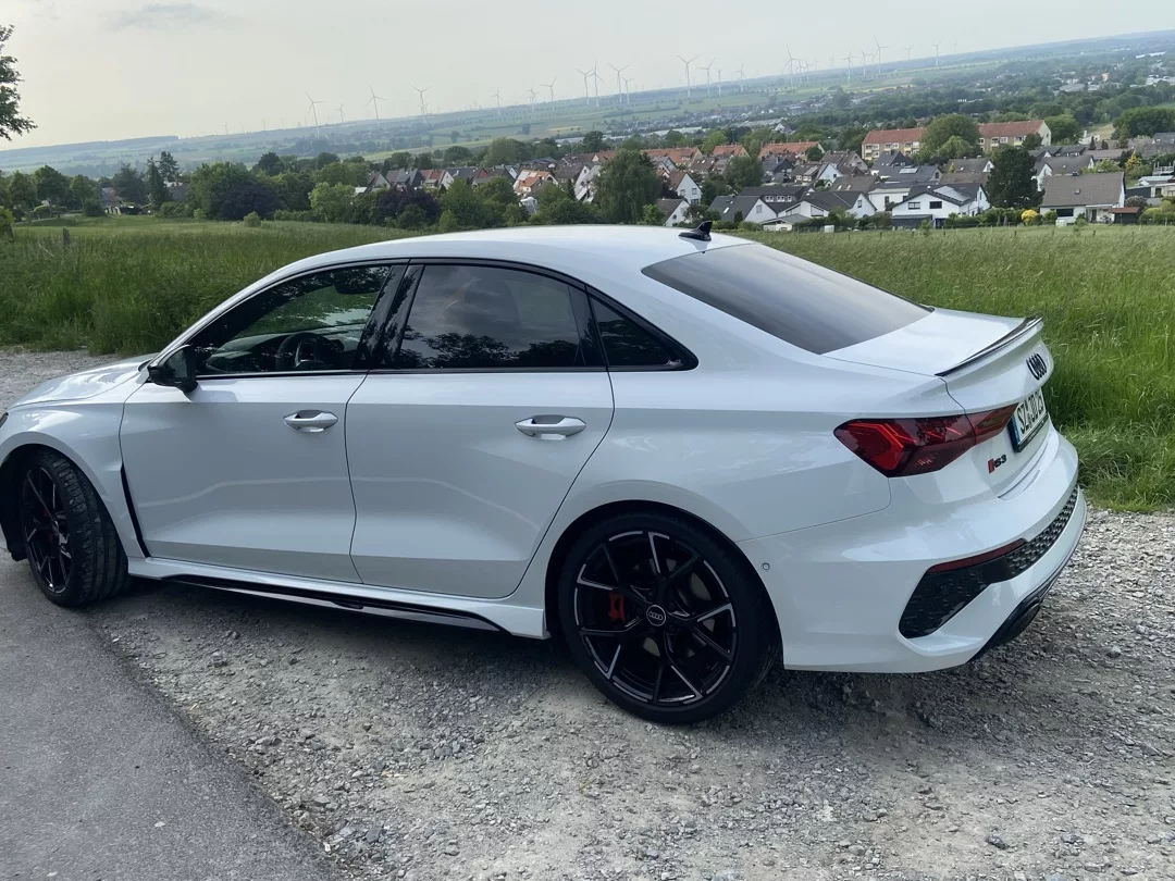 Audi RS3 Limousine in Weiß, Seitenansicht, Landschaft im Hintergrund mieten
