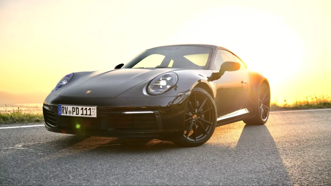 Porsche 911 - 992 Coupé in Schwarz von vorne bei Sonnenuntergang mieten