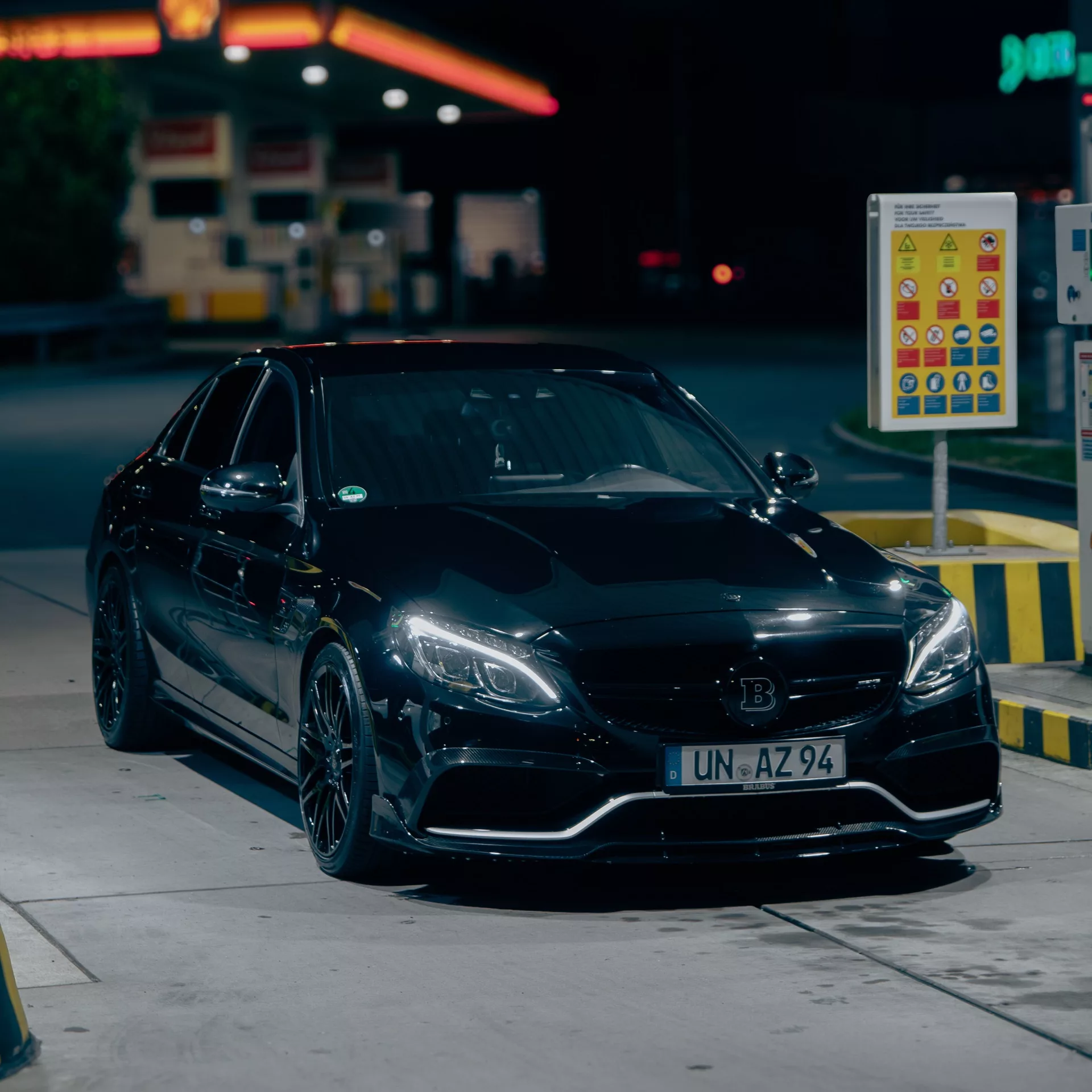 BRABUS B650 in Schwarz mieten - Frontansicht bei Nacht an Tankstelle