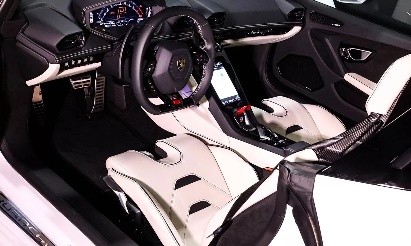Innenraum eines weißen Lamborghini Huracan EVO Spider mit modernen Bedienelementen.