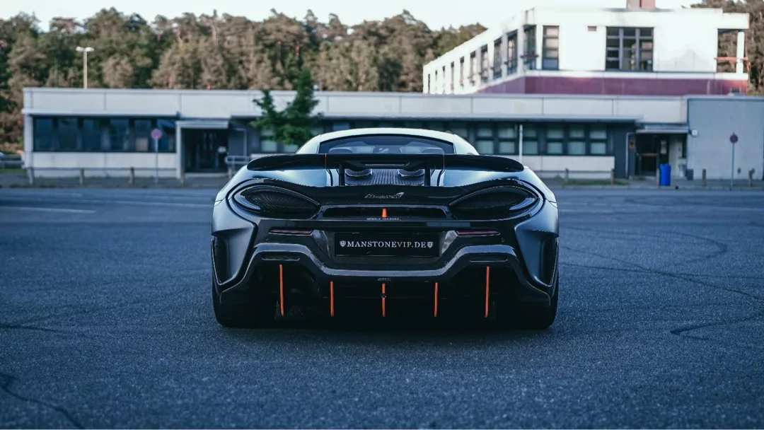 Mclaren 600LT in Schwarz, Heckansicht auf Parkplatz, mieten.