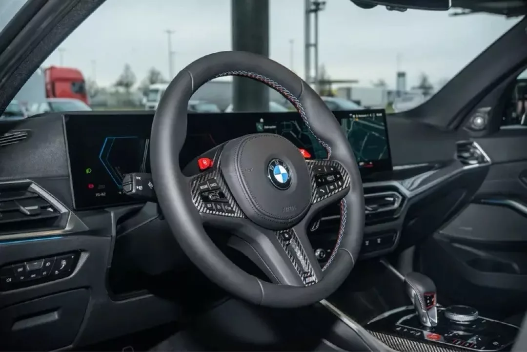 Innenraum eines BMW M3 Competition mit Fokus auf Lenkrad und Armaturenbrett.