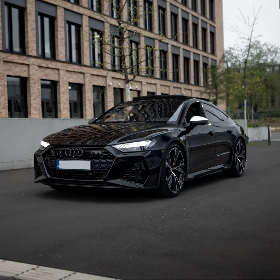 AUDI RS7 SPORTBACK in Schwarz, Frontansicht, auf Straße vor Gebäude mieten.