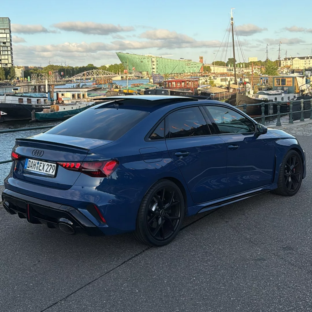 AUDI RS3 Facelift 2025 in Blau, Heckansicht am Hafen mieten.