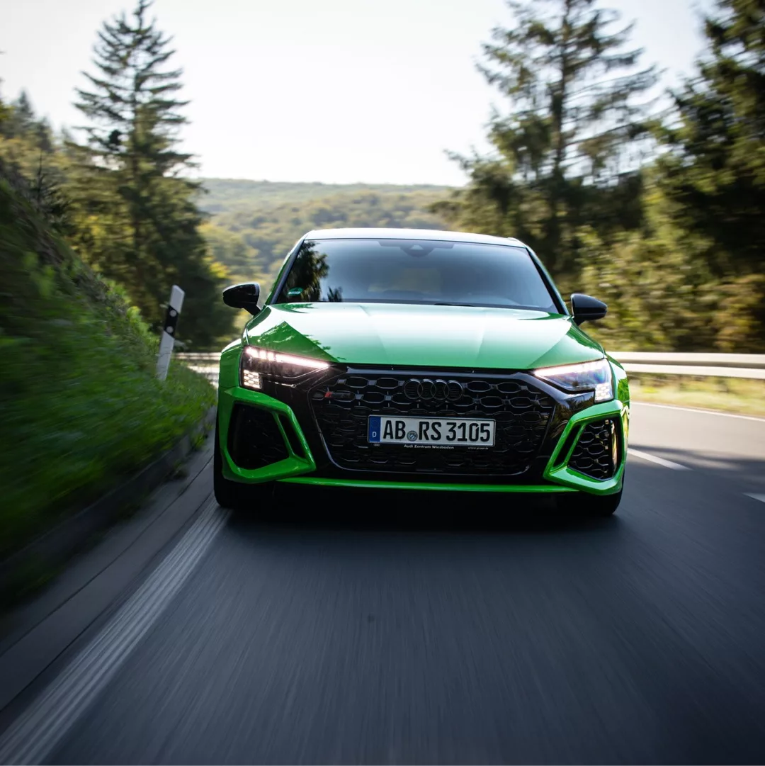 Audi RS3 Limousine in Grün frontal auf Landstraße mieten.