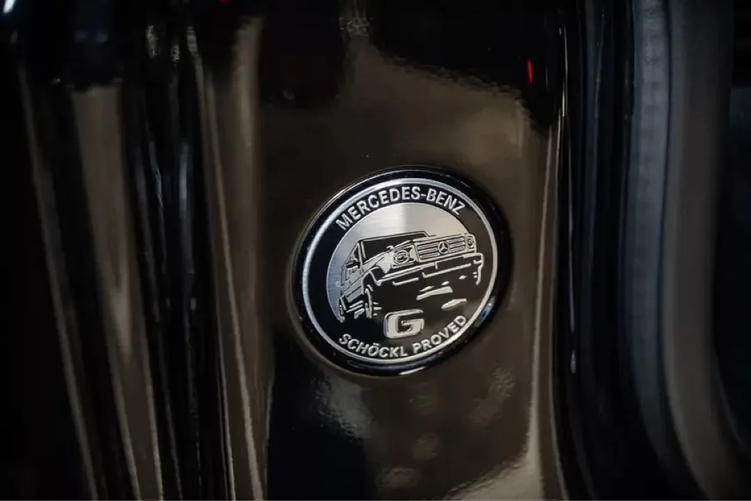 Mercedes-Benz-Emblem mit „Schöckl Proved“-Schriftzug auf glänzendem schwarzen Hintergrund.