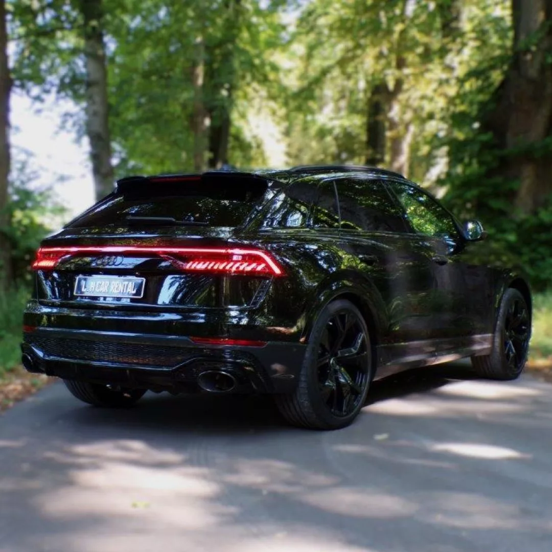 Audi RSQ8 in Schwarz von hinten auf Waldstraße mieten.
