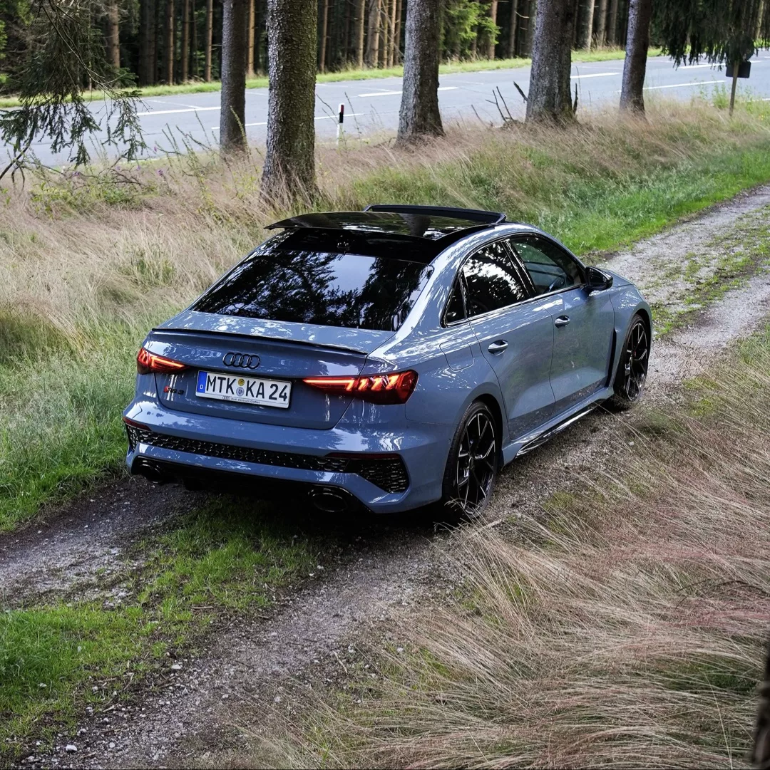 Audi RS3 in Grau auf Waldweg von hinten mieten