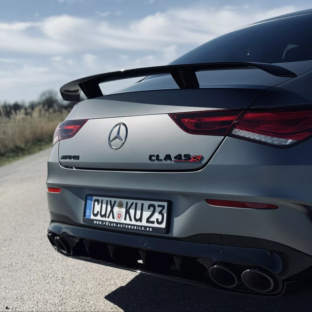 Mercedes CLA45 S AMG 4Matic+ in Grau, Heckansicht auf Landstraße mieten