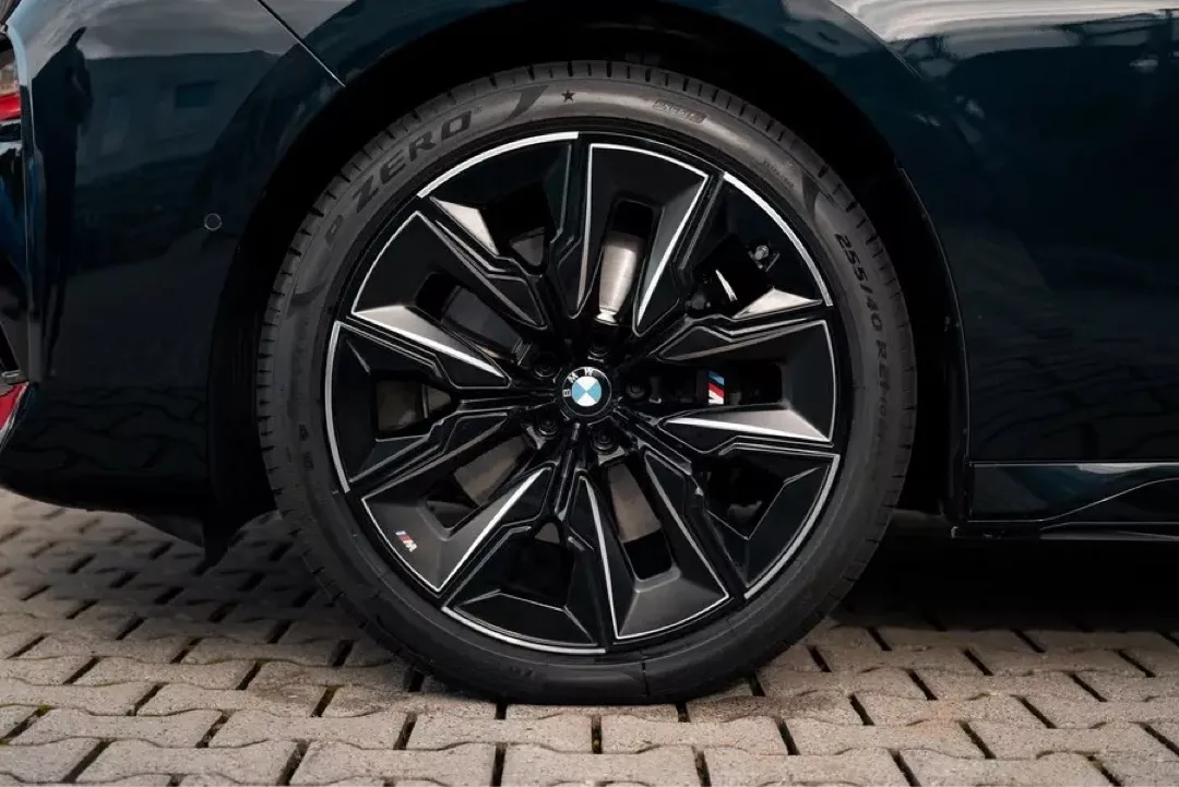 Nahaufnahme einer schwarzen BMW 740d M xDrive Felge auf Kopfsteinpflaster.