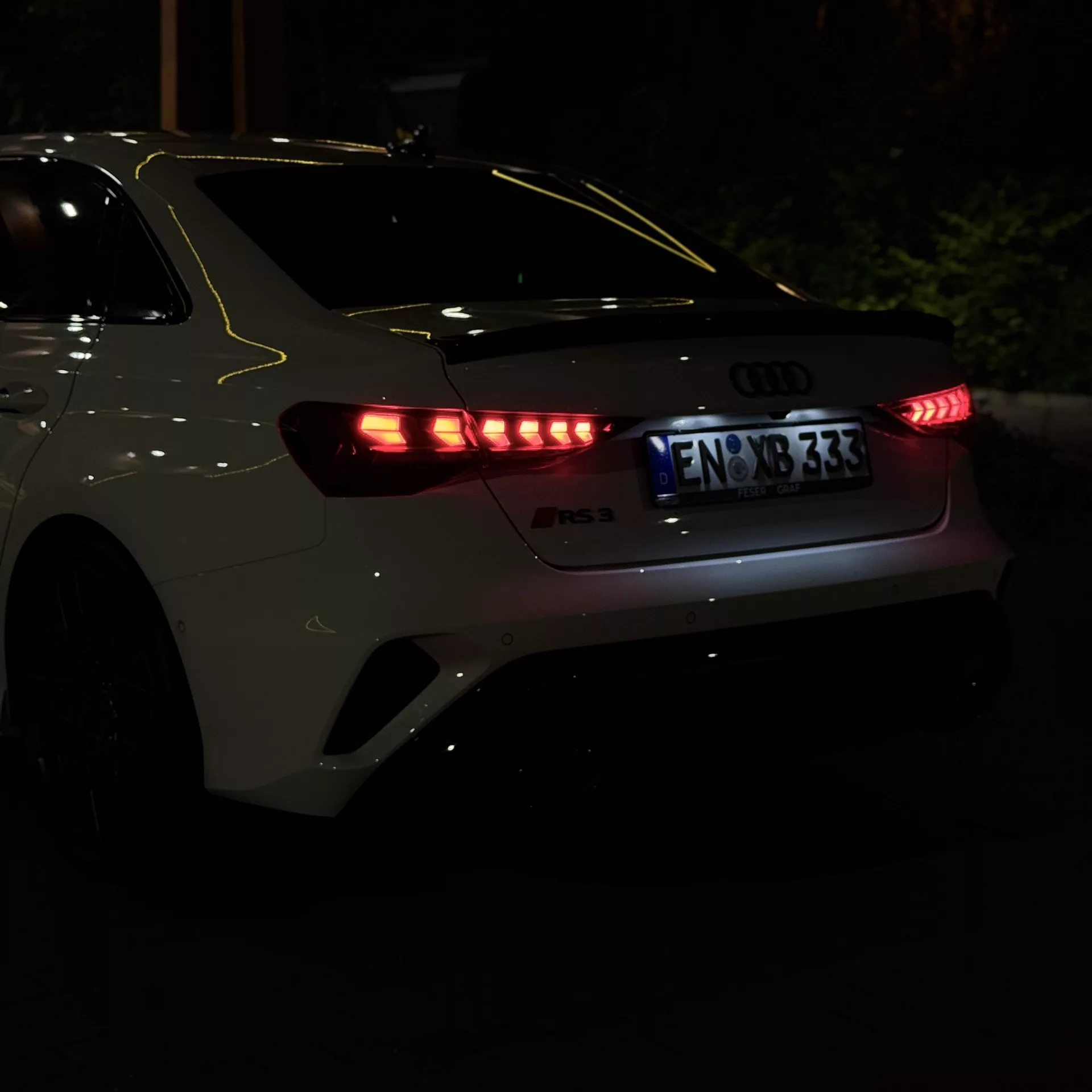 Audi RS3 Limousine 2025 mit LED-Rückleuchten in Rot bei Nacht mieten.