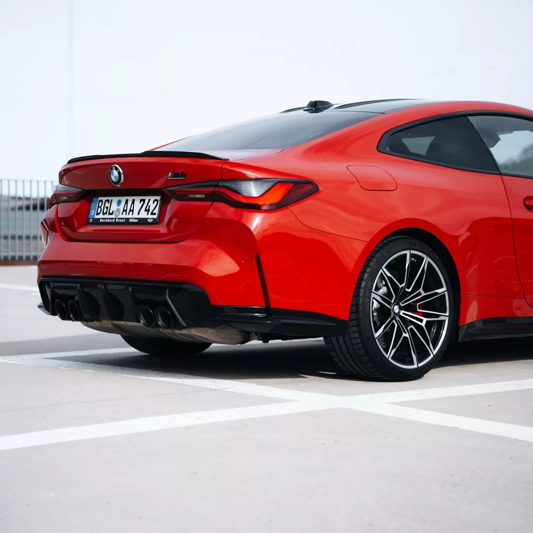 Roter BMW M4 Competition xDrive auf einem Parkplatz.