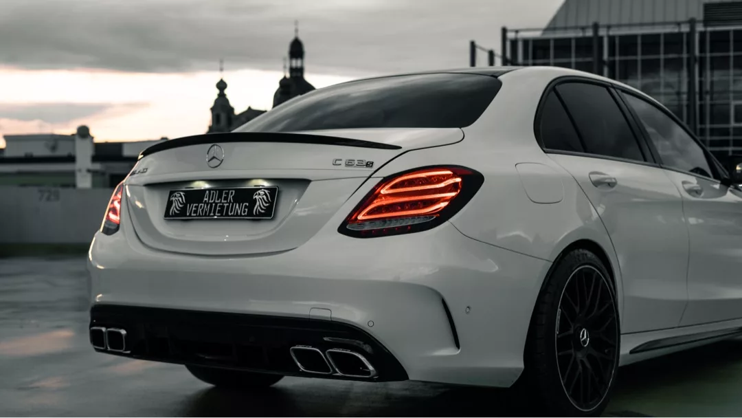 Mercedes C63 AMG in Weiß, Heckansicht bei Dämmerung mieten