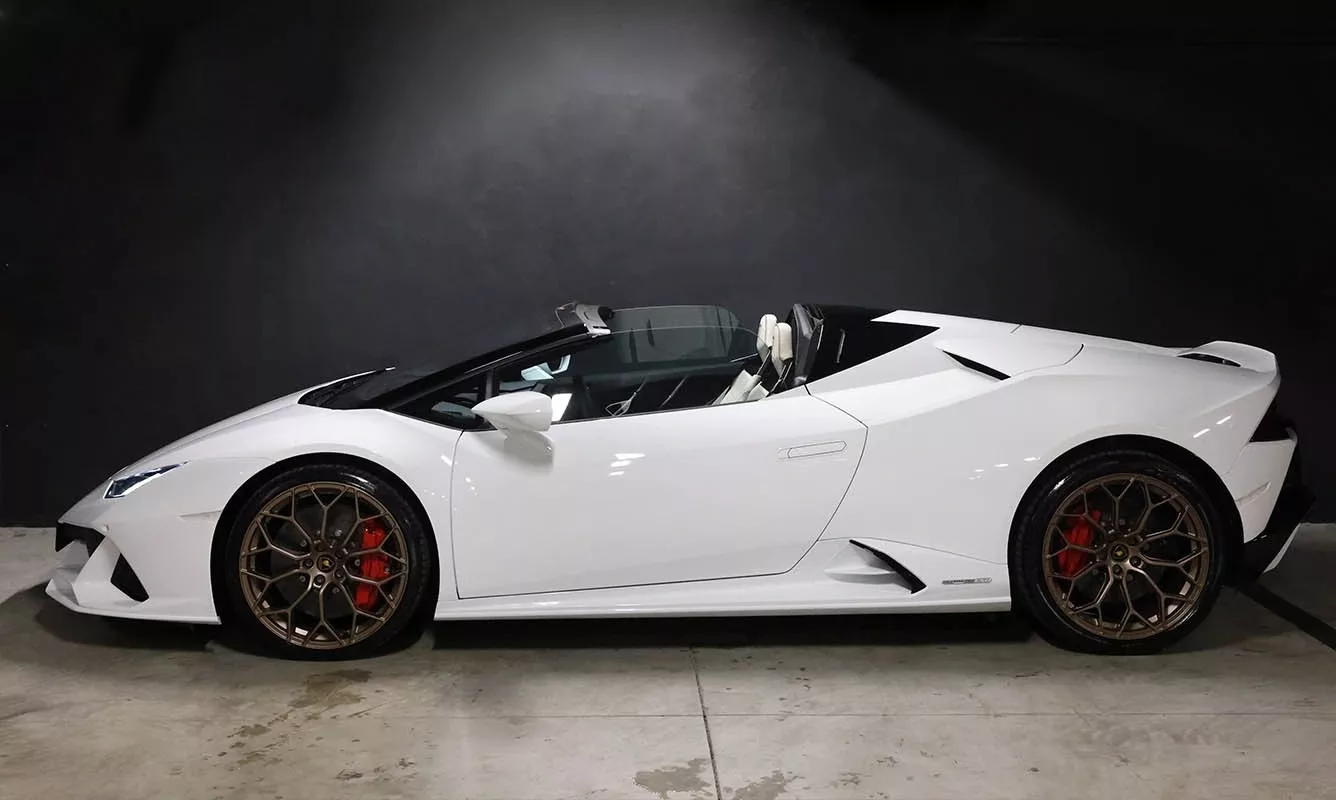 Weißer Lamborghini Huracan EVO Spider im Profil auf grauem Hintergrund.