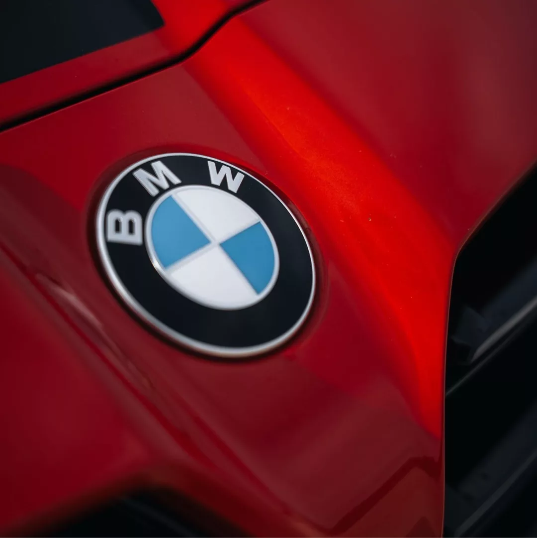 Nahaufnahme eines roten BMW M4 Competition xDrive Emblems.