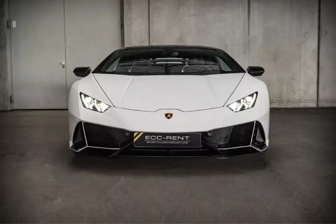 Weißer Lamborghini Huracán EVO vor einer grauen Wand in einem Parkhaus.