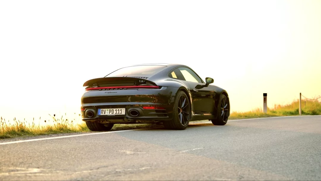 Porsche 911 - 992 Coupé in Schwarz, Heckansicht auf Straße, mieten