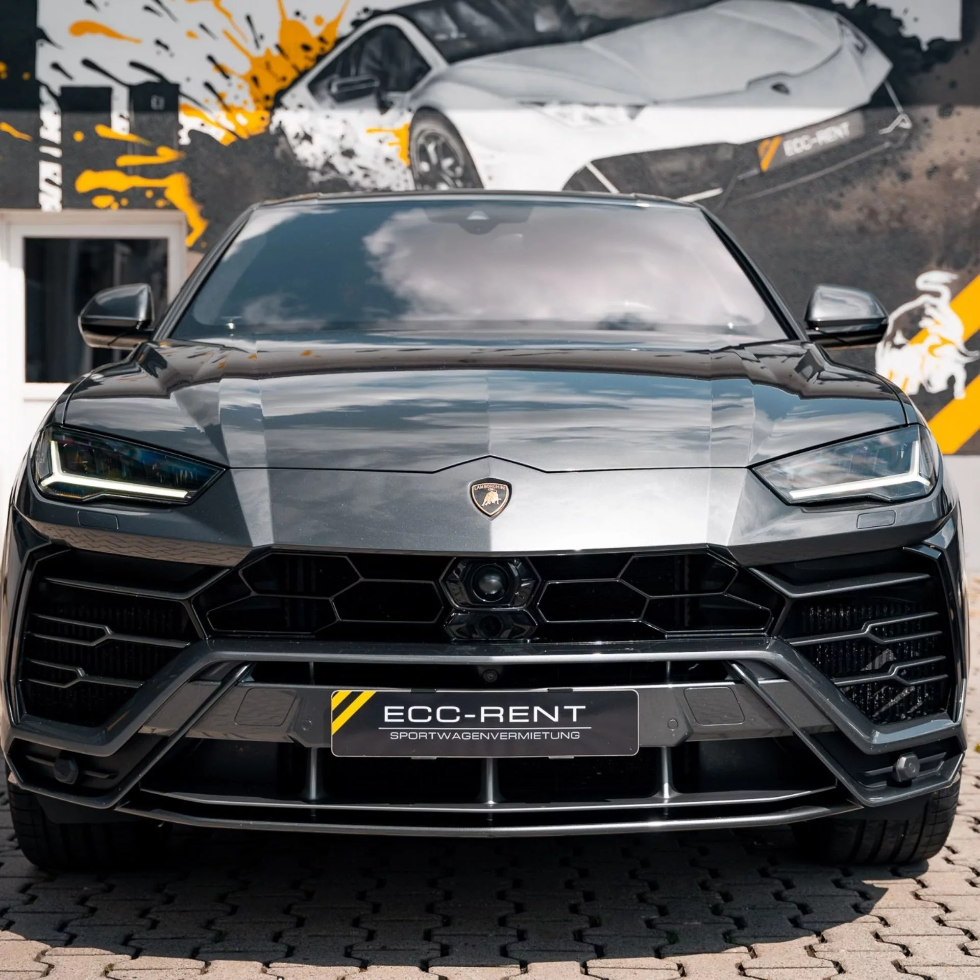 Lamborghini Urus SUV in schwarz vor künstlerischer Wand.